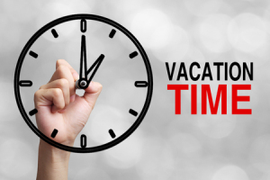 57725221 - hand is drawing a clock with text vacation time concept aside with blurred gray background.